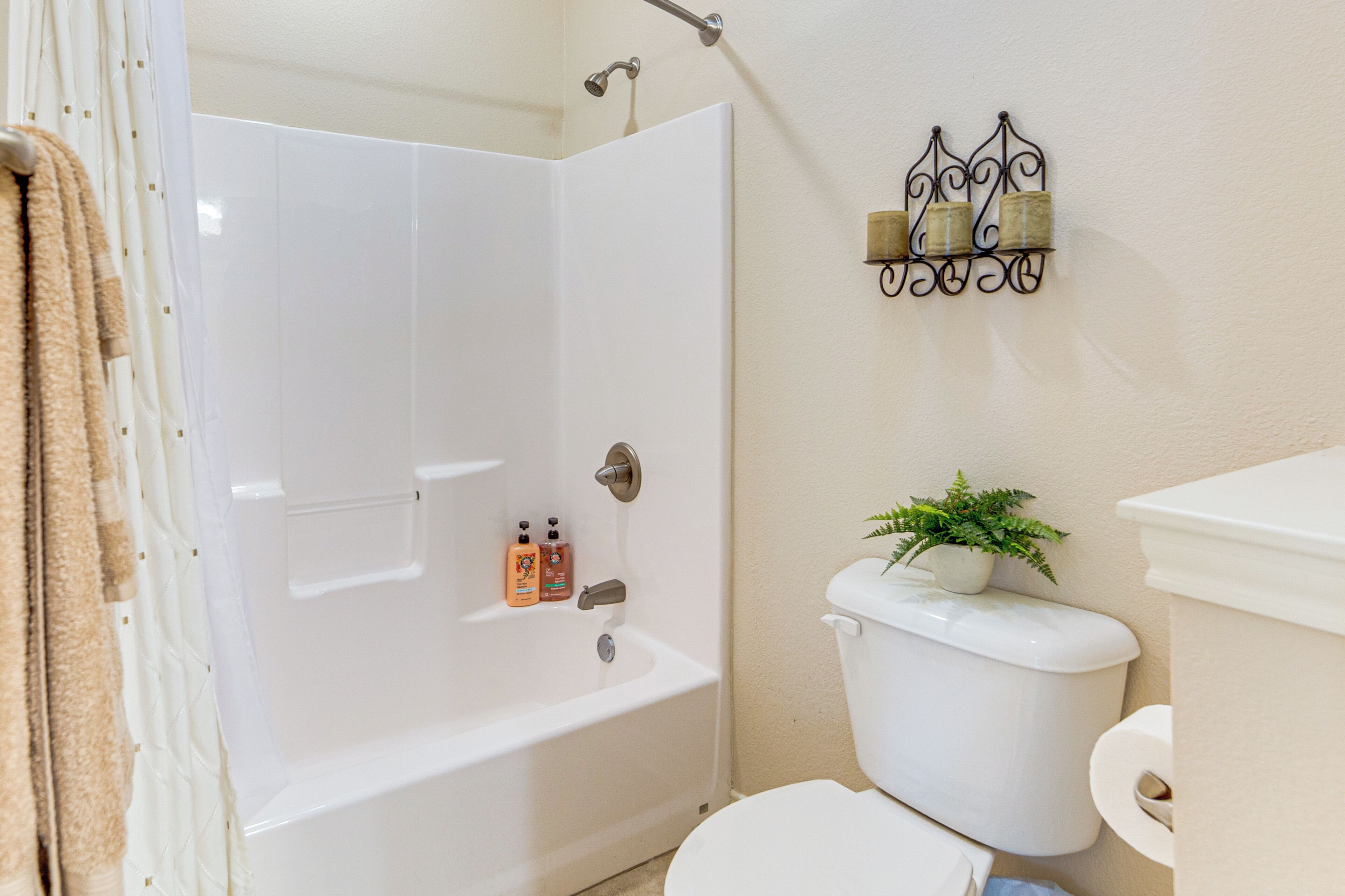 Un baño con bañera, inodoro y repisa en la pared con velas.