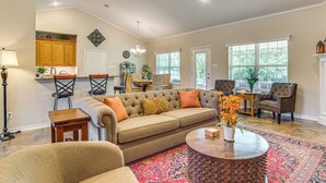 Un salon spacieux avec un canapé beige, une table basse ronde et un tapis à motifs.