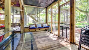 A wooden deck with a glass door leading to a covered seating area with blue cushions. - Walk to North Topsail Shores: Beach House w/ Gear! (Sneads Ferry)