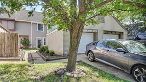 A residential driveway with a tree, a parked car, and a house with a garage. - 5 Mi to NAS Oceana: Townhome w/ Fenced Yard! (Virginia Beach)
