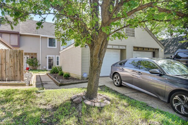 A residential driveway with a tree, a parked car, and a house with a garage.