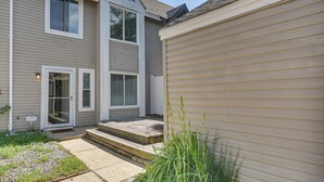 A two-story residential building with a front porch, a sliding glass door entrance, and a small garden area with stepping stones. - 5 Mi to NAS Oceana: Townhome w/ Fenced Yard! (Virginia Beach)