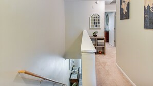 A staircase leading to a landing with a wooden handrail, a small table with a plant, and a framed map on the wall. - 5 Mi to NAS Oceana: Townhome w/ Fenced Yard! (Virginia Beach)