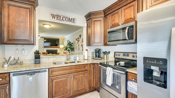 A kitchen with wooden cabinets, stainless steel appliances, a dishwasher, a microwave, and a water dispenser. - 5 Mi to NAS Oceana: Townhome w/ Fenced Yard! (Virginia Beach)