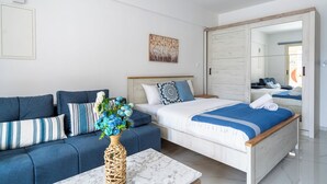 Un dormitorio moderno con cama, sofá, mesa de centro y espejo.