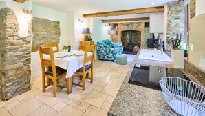 A cozy living area with a stone fireplace, wooden furniture, and a modern kitchen with granite countertops. - Host Stay Dipple Farm Cottage (Bideford)