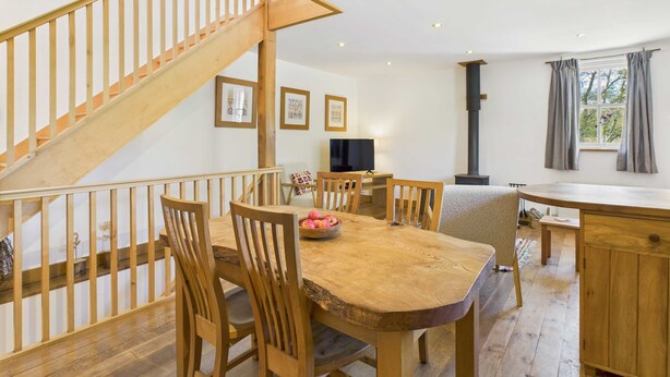 Un comedor con mobiliario de madera, una escalera y una chimenea.