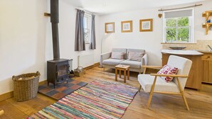 Una sala de estar acogedora con chimenea, un sofá, un sillón y una mesita.