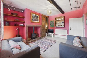 Un salon chaleureux avec une cheminée, un canapé, un téléviseur et des étagères ornées d’objets décoratifs.