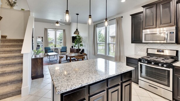 A modern kitchen with granite countertops, stainless steel appliances, and dark cabinetry. - Luxury 4BR 2 5BA Home EV Charger Pool Access (Buda)