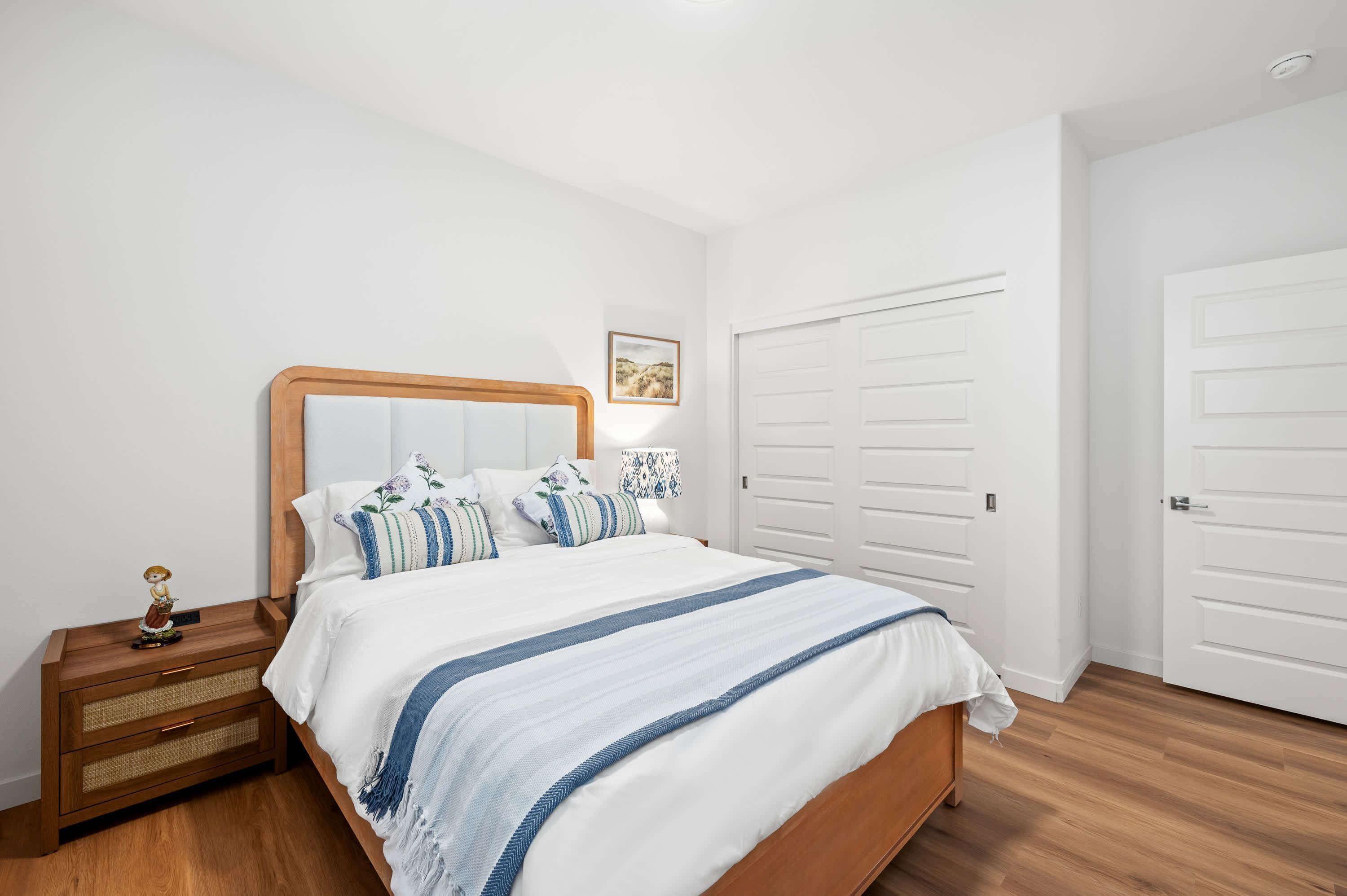 A bedroom with a wooden bed, white walls, and a white door.