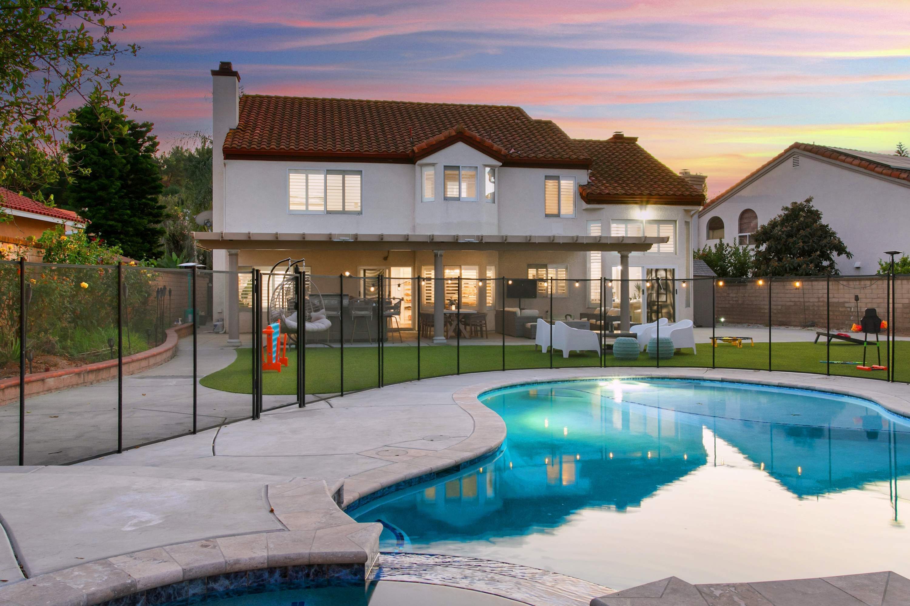 A large house with a swimming pool, a patio, and a well-maintained lawn.