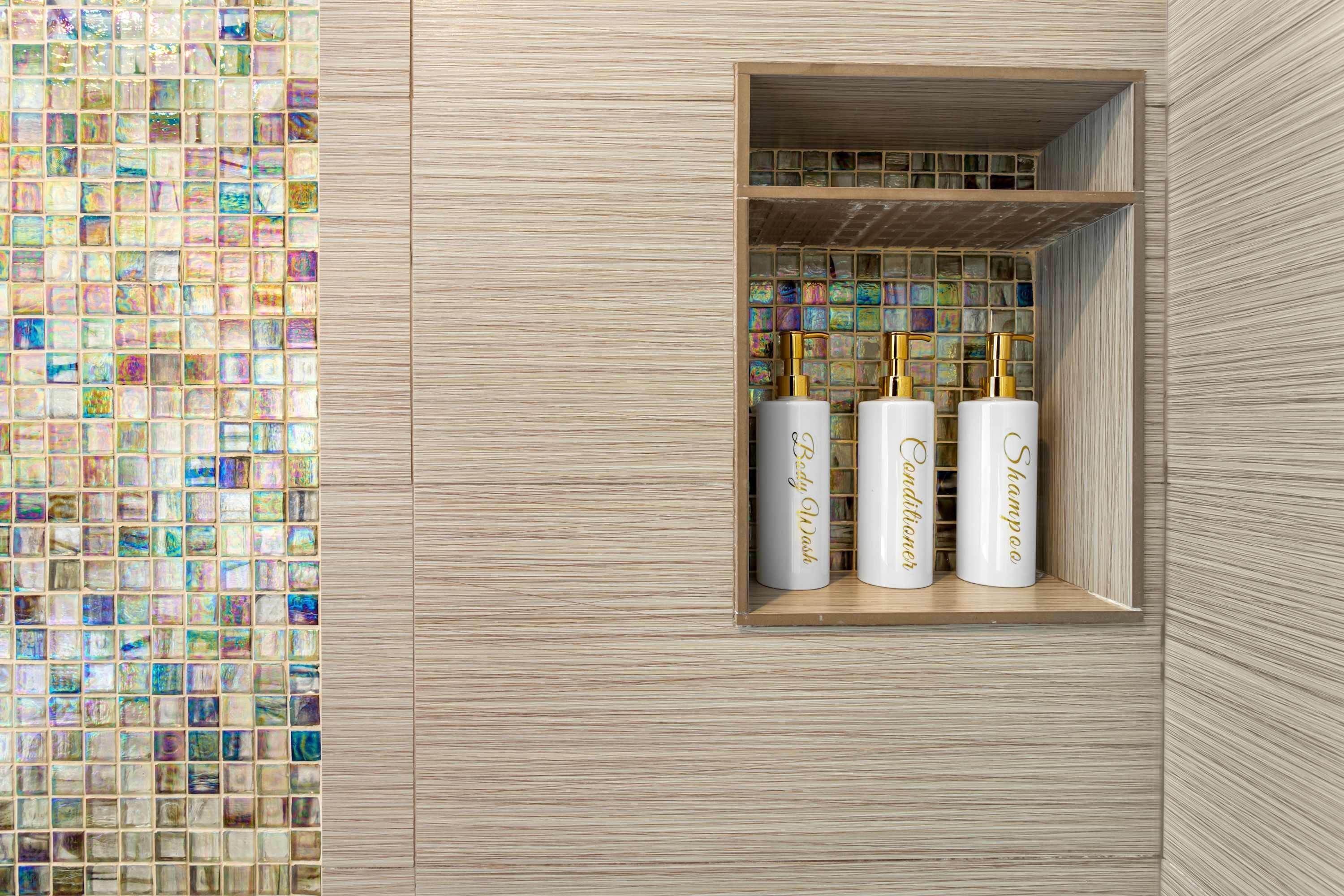 A bathroom with a wooden vanity, a mirror, and three white bottles labeled "Baby Bliss Conditioner," "Baby Bliss Shampoo," and "Baby Bliss Body Wash."