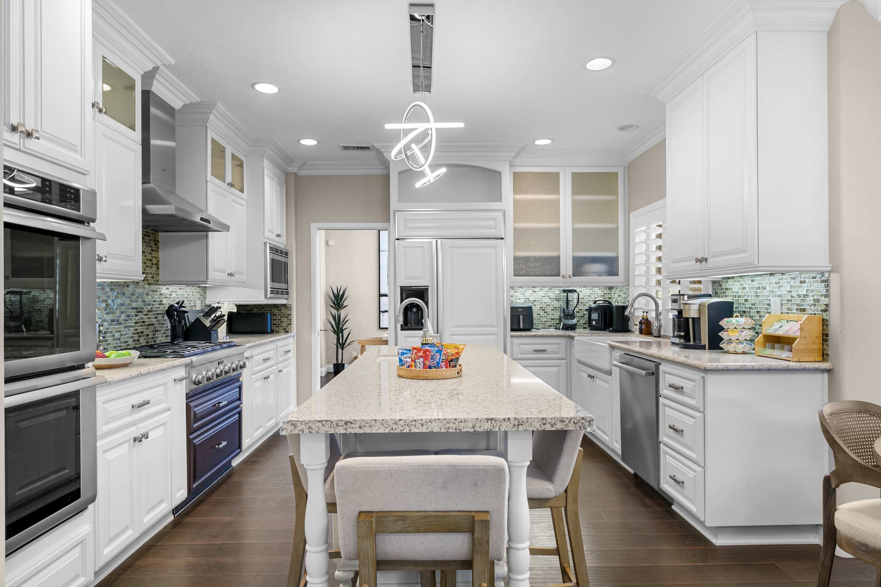 Una cocina moderna con armarios blancos, una isla central y electrodomésticos de acero inoxidable.