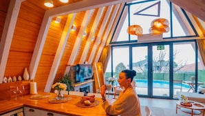 Uma cozinha moderna com uma janela ampla, teto de madeira e área de jantar com vista para uma piscina.