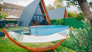 Uma casa moderna com piscina, rede e muro de pedra.