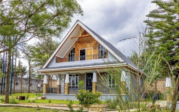 A two-story house with a sloped roof, large windows, and a balcony. - The Cabin Azure (Naivasha)