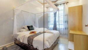 A bedroom with a four-poster bed, a bedside table, a wardrobe, and a window with curtains. - The Cabin Azure (Naivasha)
