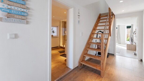 A staircase with a wooden handrail leading to a second floor. - Holiday Home 'Küstenliebe' with Private Terrace, Private Garden and Wi-Fi (Fehmarn)