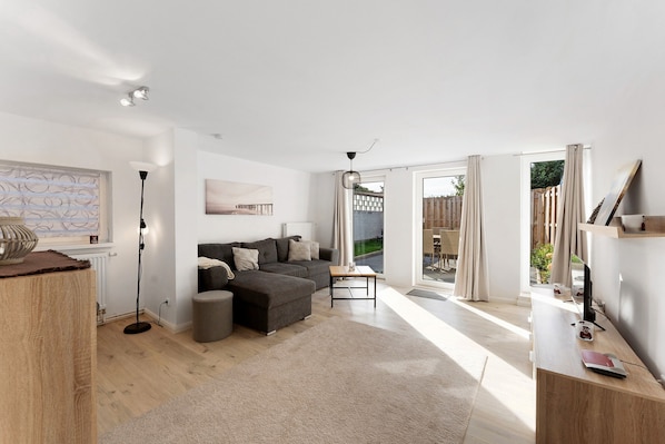 A modern living room with a sectional sofa, a standing lamp, and a wooden coffee table.