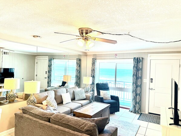 A living room with a ceiling fan, a sofa, a coffee table, and a TV.