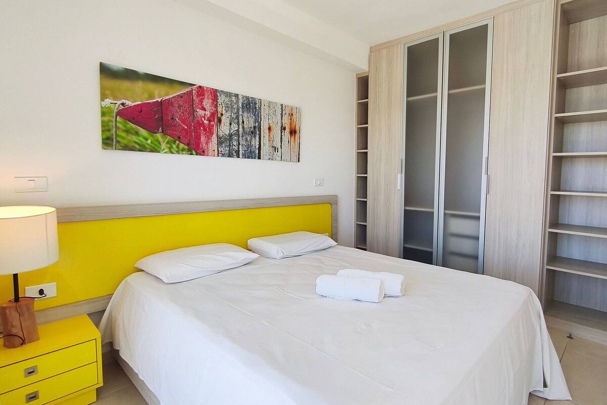 Une chambre d’hôtel avec un lit, une table de chevet, une lampe, une armoire et un tableau au mur.