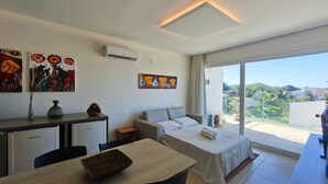 Habitación de hotel con cama, escritorio, silla, una mesita y cuadros en las paredes.