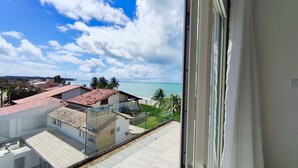 Vista desde una ventana sobre una zona costera con edificios, cielo despejado y una playa.