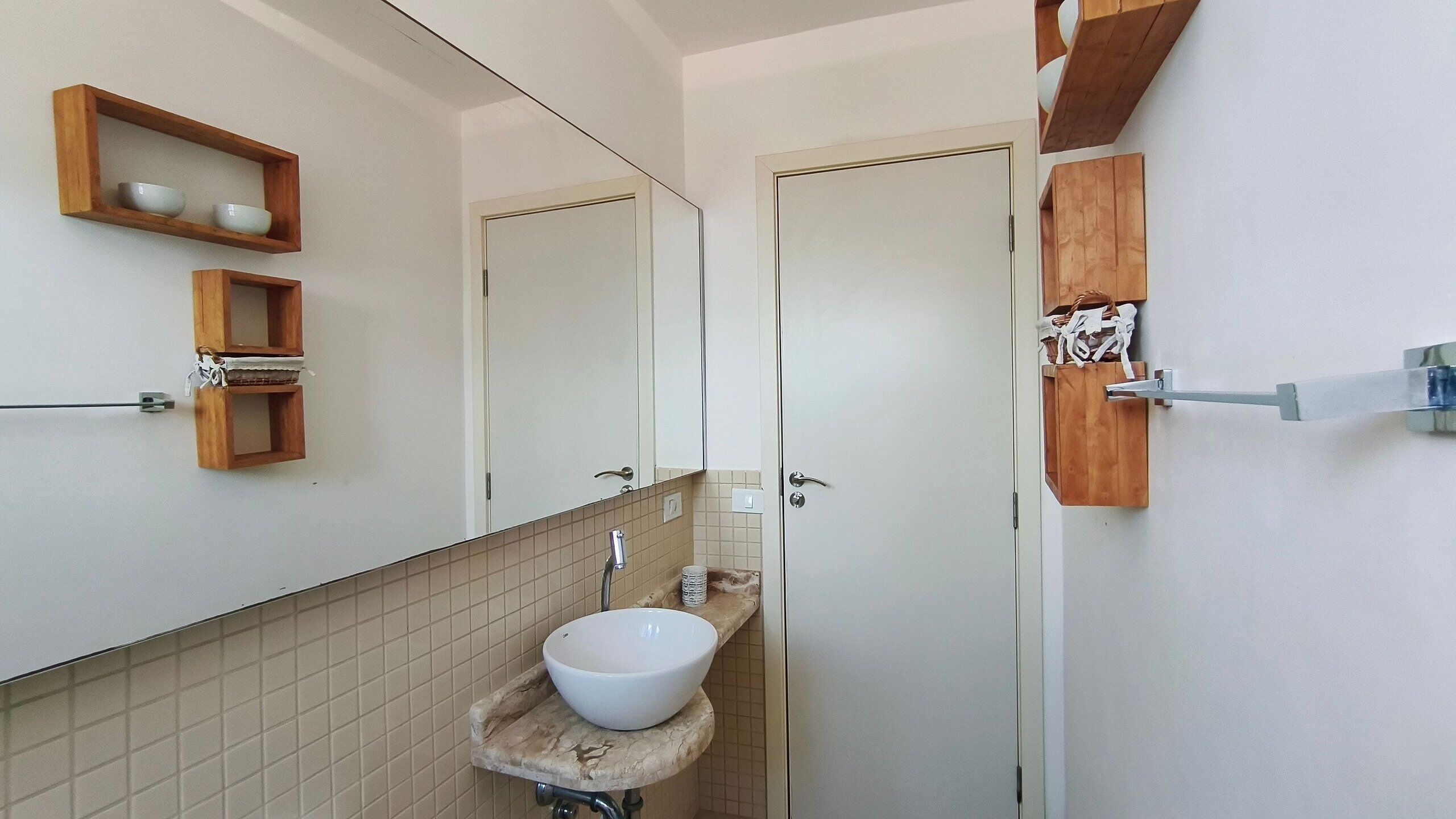A bathroom with a sink, mirror, and wooden shelves.