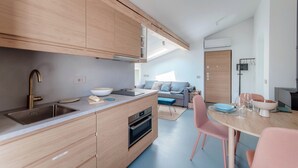 Una cucina moderna con mobili in legno, forno integrato e zona pranzo con sedie rosa e un tavolo.