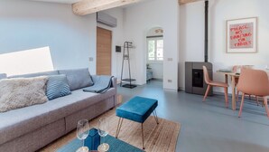 Un soggiorno moderno con un divano grigio, un poggiapiedi blu e un'area pranzo con tavolo e sedie.