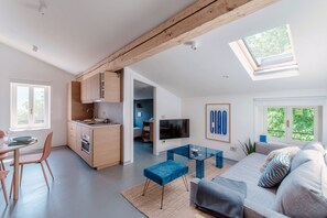 A modern living space with a kitchen, dining area, and a cozy seating area with a TV and artwork. - Luce (Acquaseria)