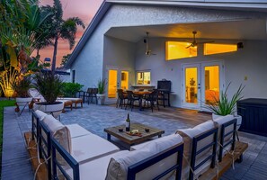 Un patio con mobiliario exterior, una zona de comedor y un ventilador de techo.