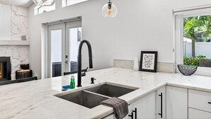 A modern kitchen with a large island, white cabinetry, a black faucet, and pendant lighting.