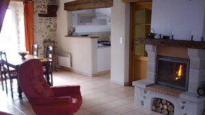 Un salon avec une cheminée, un coin repas et une cuisine à l’arrière-plan.