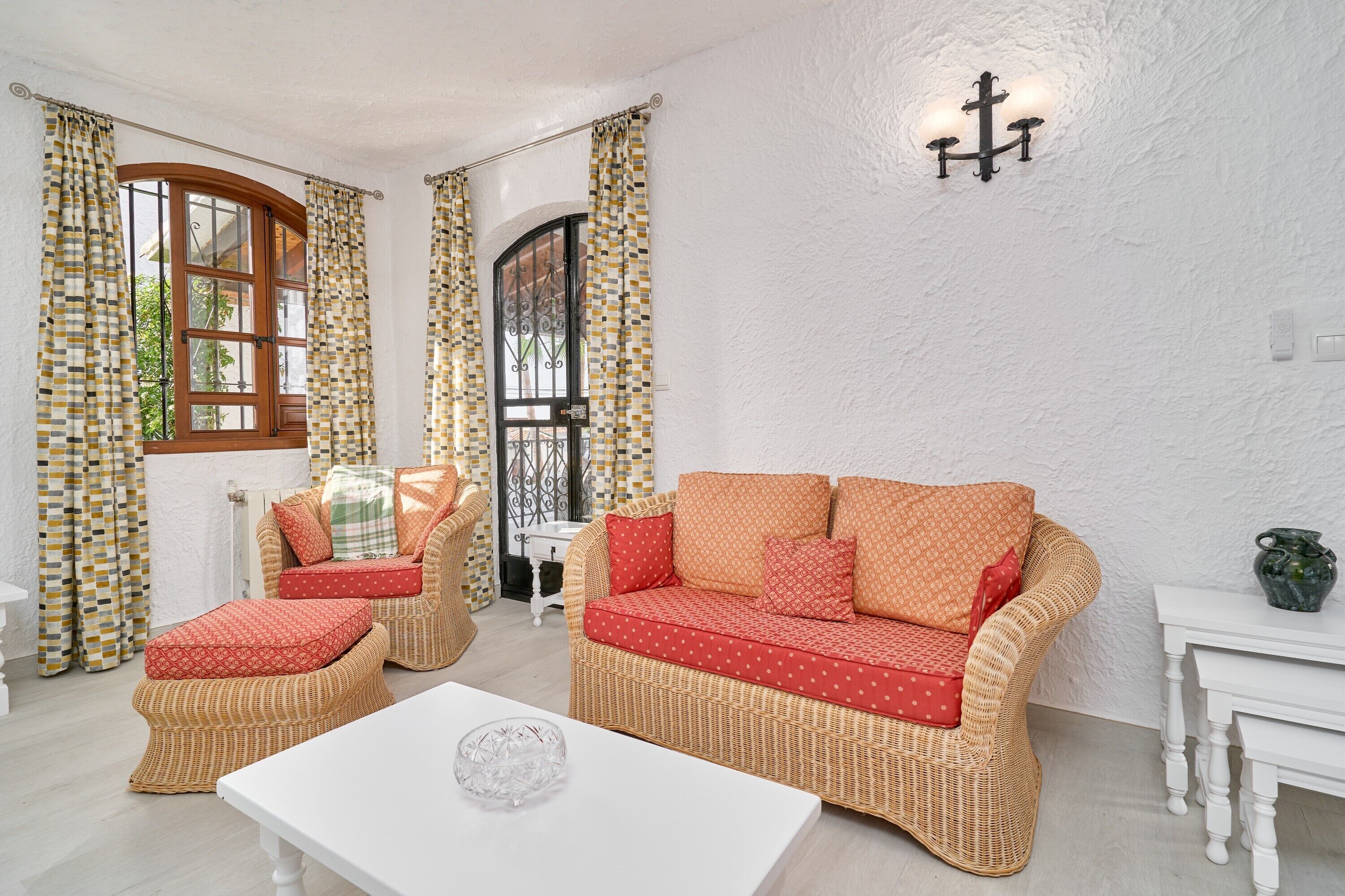 A room with a wicker sofa, matching ottoman, and a white coffee table.