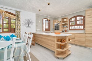 Een moderne keuken met houten kastjes, een centraal eiland en een eetgedeelte met witte stoelen en een tafel.
