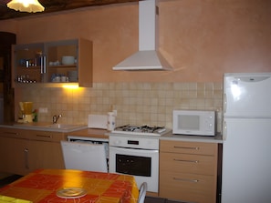 Une cuisine équipée d’une cuisinière à gaz, d’un four à micro-ondes, d’un lave-vaisselle et d’une table recouverte d’une nappe.