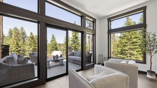 Een modern interieur met grote ramen, een balkon met buitenmeubilair en een potplant.