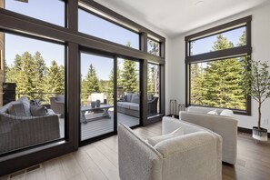 Un interior moderno con ventanas amplias, un balcón con mobiliario exterior y una planta en maceta.