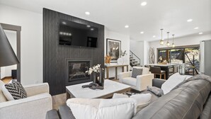 Een moderne woonkamer met een open haard, bank, salontafel en een eetgedeelte met uitzicht.
