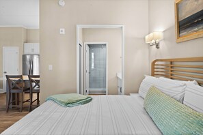 A hotel room with a bed, a desk, and a shower.