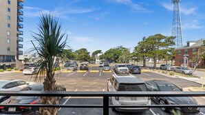 Un parking avec plusieurs voitures, un palmier et des bâtiments en arrière-plan.