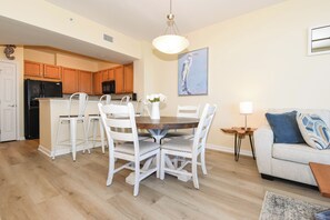 Une cuisine moderne avec des meubles en bois, un réfrigérateur noir et un coin repas comprenant des chaises blanches et une table ronde.