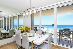 A dining area with a white table, chairs, and a view of the ocean. - 7th Floor Beachfront Condo w/ Beach Service in Destin! 🐚🌴🐬 (Destin)