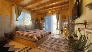 Ein gemütliches Schlafzimmer mit Holzbalkendecke, einem Bett mit kariertem Überwurf, einem kleinen Tisch und einem Blumentopf.