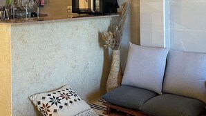 Una habitación acogedora con techo de madera, un sofá, una mesita pequeña, un jarrón decorativo y un microondas.