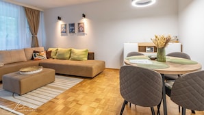 A modern living room with a sofa, ottoman, and dining table with chairs.