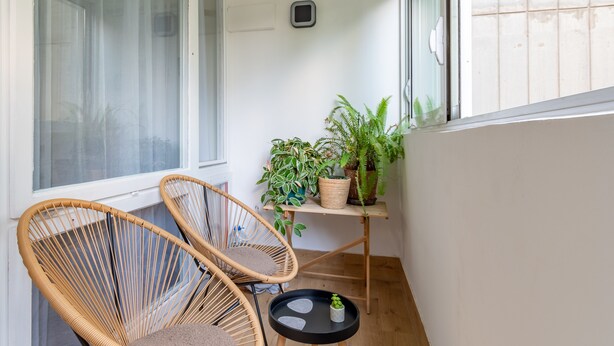 A balcony with two wicker chairs, a small table, and potted plants.