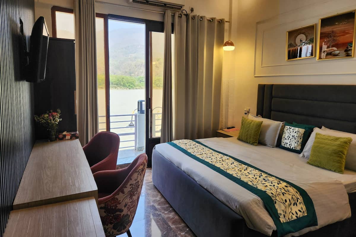 A hotel room with a bed, a desk, a chair, and a view of the outdoors.